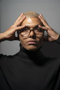 Young man with head in hands against gray background