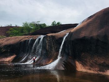 Man surfing on waterfall against sky