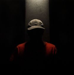 Portrait of man standing against black background