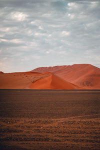 Scenic view of desert against cloudy sky