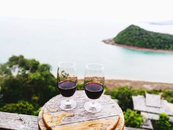 Close-up of wine glass on table against sea