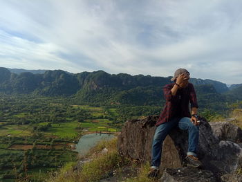 Rear view of women sitting on mountain against sky