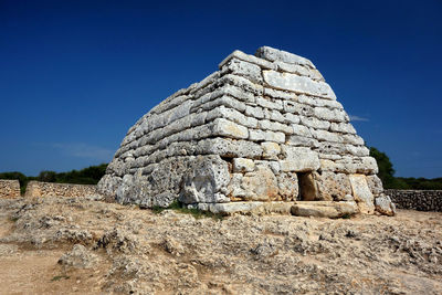 Low angle view of old ruin on field against clear blue sky