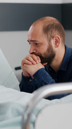 Man praying while sitting in hospital