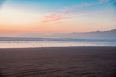Scenic view of beach against sky during sunset