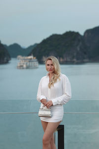 Young woman standing against sea