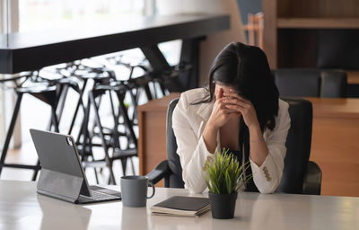 Woman using phone while sitting on table