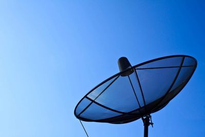 Low angle view of telephone pole against clear blue sky