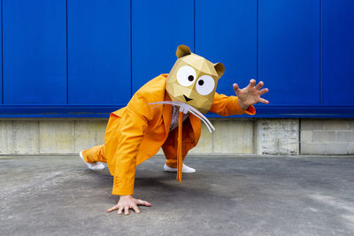 Full length of person wearing mask against blue wall