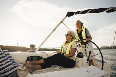 Cheerful senior female friends in boat on sunny day