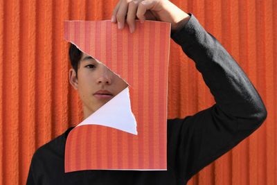 Portrait of young man standing against orange wall