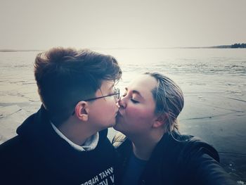 Man kissing woman against sea at beach