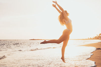 Full length of woman jumping at beach