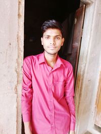 Portrait of young man standing against door