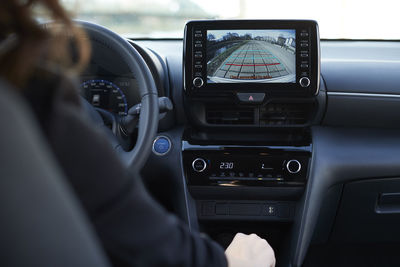 Businesswoman parking car through digital display of backup camera