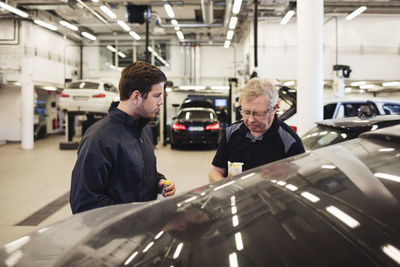 Mechanics talking while standing in auto repair shop