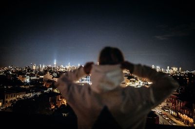 Rear view of couple against illuminated cityscape