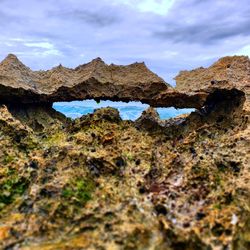 Rock formation on land against sky and ocean waves.