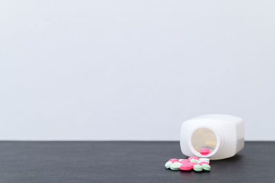 Close-up of white bottle on table against wall