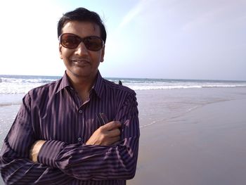 Portrait of young man at beach against sky