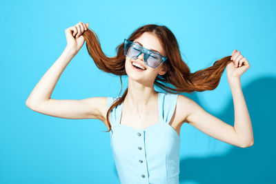 Young woman wearing sunglasses against blue background