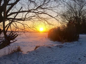 Scenic view of snow covered land during sunset
