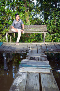 Full length of man looking away while sitting on bench in park