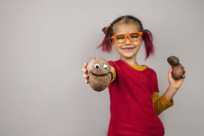 Portrait of a smiling girl standing against gray background