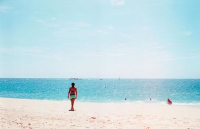 Rear view of women walking on beach against clear sky