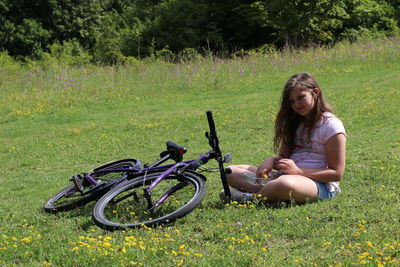 Woman sitting on bicycle in grassy field