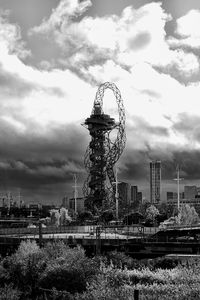 Ferris wheel in city against cloudy sky