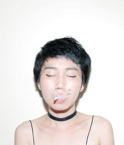 Close-up of woman emitting smoke while smoking cigarette