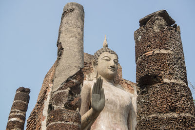 Low angle view of statue against historic building against sky