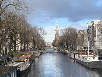 Canal amidst buildings in city against sky