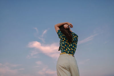 Back view young stylish mindful female under sky at sundown