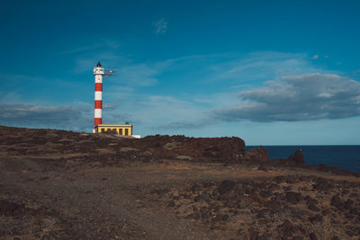 Lighthouse by sea against sky