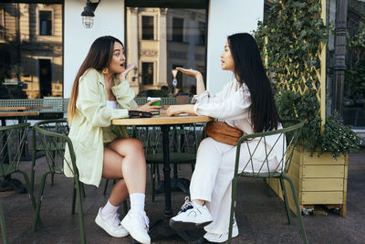 Young women talking while sitting at sidewalk cafe