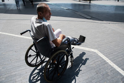 Middle-aged man with a broken leg in a cast in a wheelchair on a walk