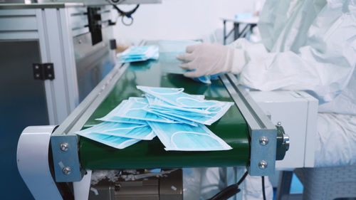 Midsection of person making surgical mask at factory