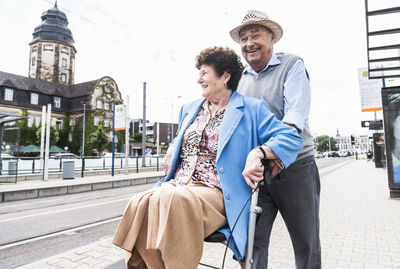 Germany, mannheim, happy senior couple with wheeled walker waiting at station