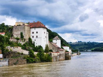 Buildings by river against sky