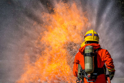 Rear view of firefighter spraying water