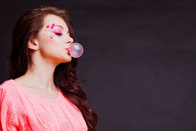 Close-up of beautiful young woman over black background