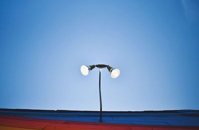 Low angle view of illuminated street light against clear blue sky