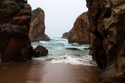 Rock formation on beach against sky