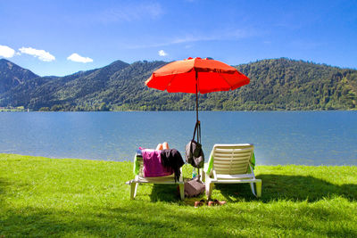 View of people sitting on chair by lake against sky