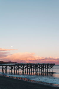 Pier over sea against sky during sunset