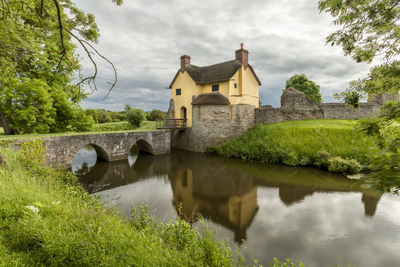 Arch bridge over lake by building against sky