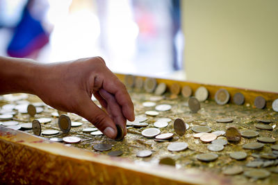 Cropped image of hand holding coins on table