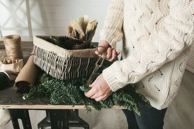 Midsection of woman cutting pine needles at home